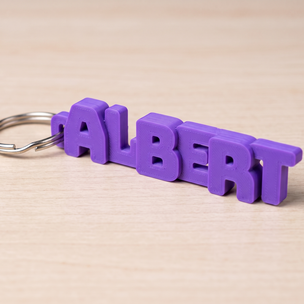 Purple custom 3D printed name keychain reading ALBERT on a wooden table