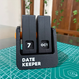 Black Date Keeper 3D printed perpetual flip desk calendar showing 7 Oct