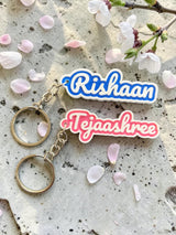 Rishaan and Tejaashree 2-colour name keychains on stone with flower petals