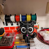 Swag Layers PurrRest black 3D printed cat glasses holder with large eyes wearing gold-rimmed spectacles on a desk